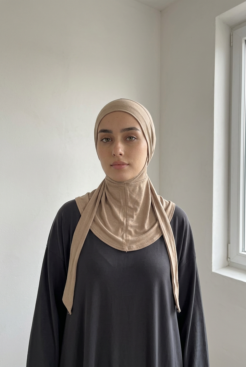 Femme portant le hijab cagoule seul, de face, les deux liens tombant devant, dans une pièce claire
