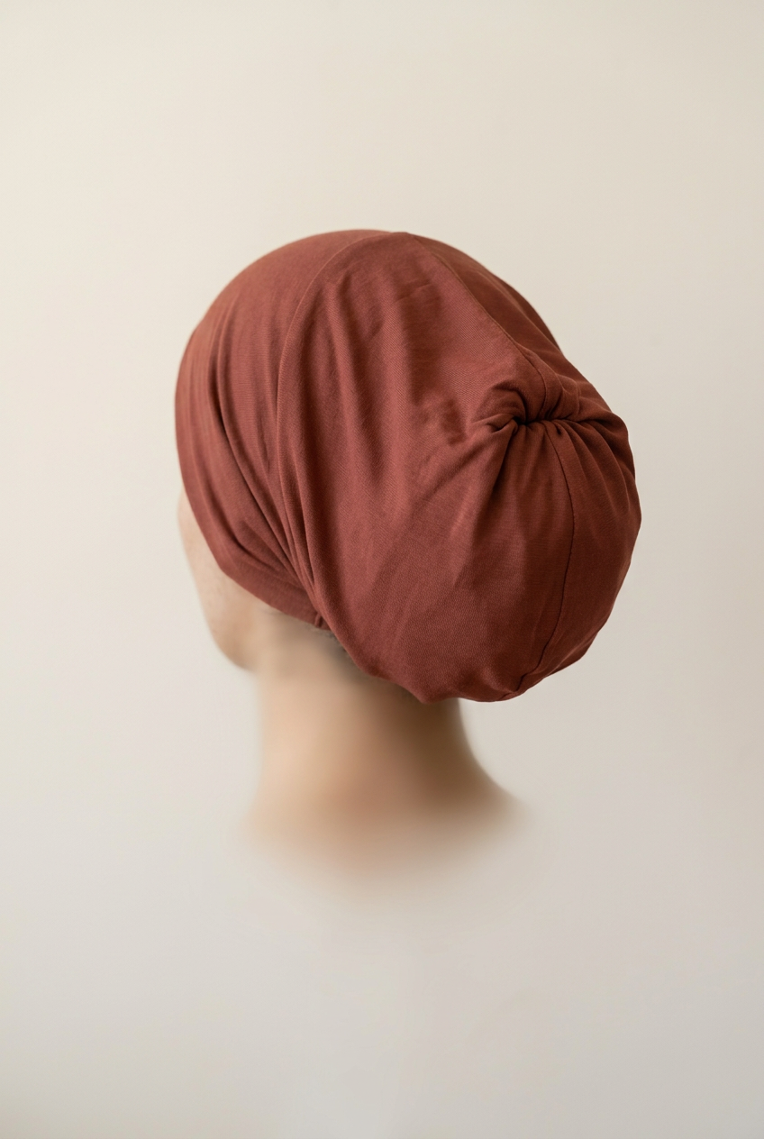Bonnet tube hijab vu de dos, le haut replié, sur fond beige uni