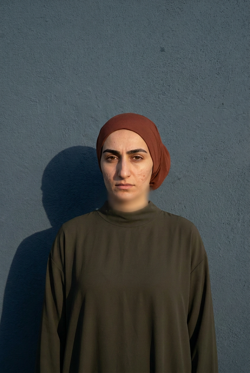 Bonnet tube hijab porté, vu de face, devant un mur bleu-gris
