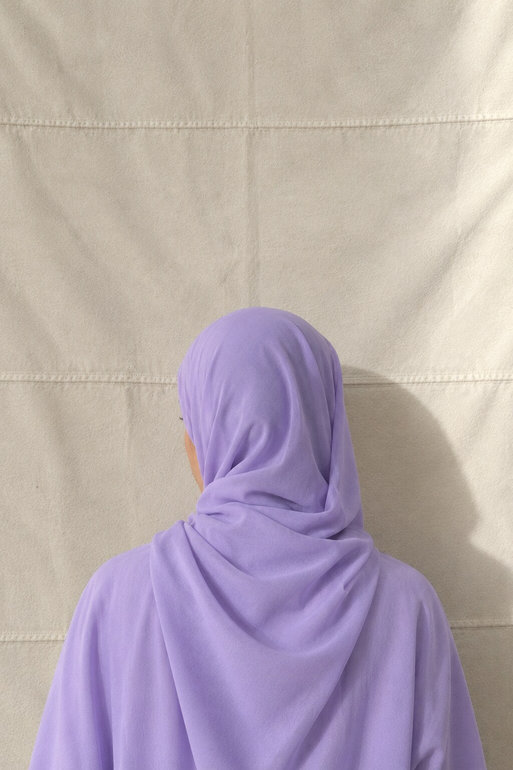 Hijab mousseline lilas vu de dos, le pan tombant sur l'épaule